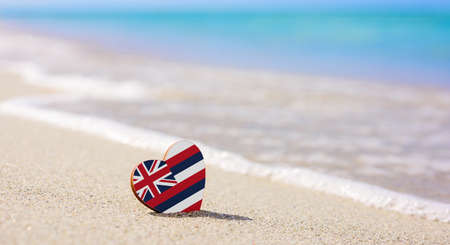 Flag of the Hawaiian Islands in the shape of a heart on a sandy beach. The concept of the best vacation in Hawaiiの写真素材