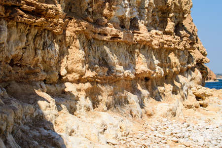 Rocky seashore close up. Geological section with different rocks. Side view. selective focus in the center of the frame.の写真素材