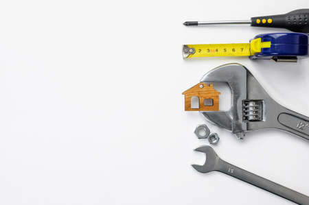 Construction tools and a small house sandwiched in a key on a white background. On the left is an empty space.の写真素材