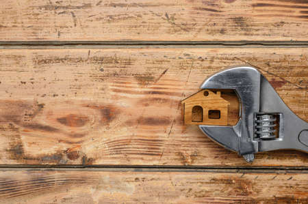 Home maintenance and repair service concept. Wrench and house model on a wooden background.の写真素材
