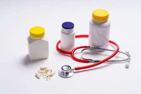 The concept of treatment during illness. White jar with goodies and a stethoscope on a light background. View from above.の写真素材