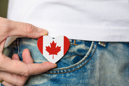 Patriot of Canada! Wooden badge with the flag of Canada in the shape of a heart in a man's hand.の写真素材