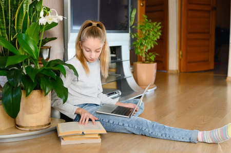 The girl reads the textbook attentively during home schooling. The girl is sitting in the room.の写真素材