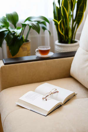 Opened paper book with glasses on a beige sofa. Selective focus on glasses.の写真素材