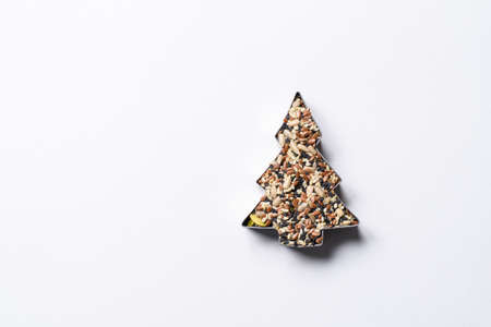 Form for cookies in the shape of a Christmas tree full of seeds on a white background. Top view, focusing on seedsの写真素材