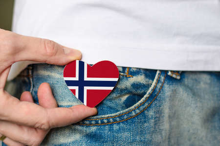 Patriot of the Norway! Wooden badge with Norway flag in the shape of a heart in a man's hand.の写真素材
