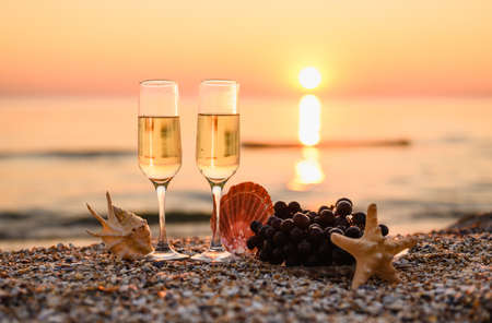 Romantic evening on February 14 by the sea. Glasses of champagne at sunset. Selective focus on wine glass, narrow focus.の写真素材