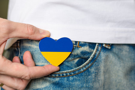 Patriot of Ukraine! Wooden badge with the flag of Ukraine in the shape of a heart in a man's hand. National holiday of Ukraine.の写真素材