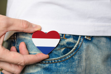 I am a patriot of the Netherlands! Wooden badge with Netherlands flag in the shape of a heart in a man's hand.の写真素材