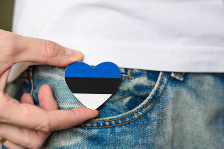 Patriot and citizen of the Estonia! Wooden badge with Estonia flag in the shape of a heart in a man's hand.の写真素材
