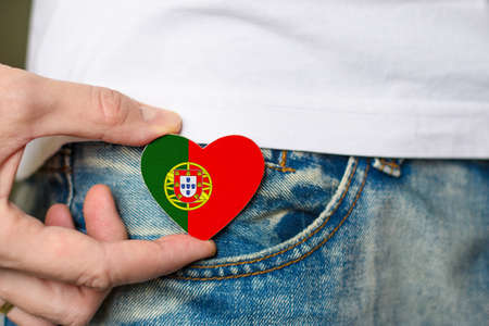 Patriot of Portugal! Wooden badge with flag of Portugal in the shape of a heart in a man's hand.の写真素材