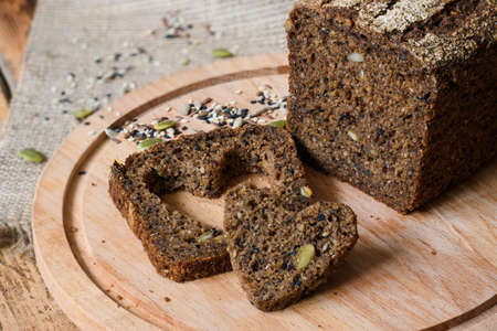 Fresh healthy rye bread next to a heart-shaped slice. Healthy food concept. Top view, Selective focus on a slice of bread.の写真素材