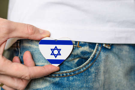 Patriot of the Israel! Wooden badge with Israel flag in the shape of a heart in a man's hand.の写真素材
