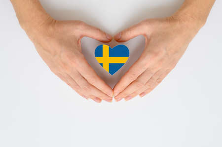 The national flag of Sweden in female hands. The concept of patriotism, respect and solidarity with the citizens of Sweden.の写真素材