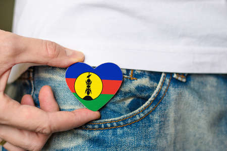 Patriot of the New Caledonia! Wooden badge with New Caledonian Flag in the shape of a heart in a man's hand.の写真素材
