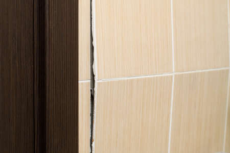 Poor quality work in the bathroom. Tiles are falling off the wall. Crack in the wall. Selective focus on the crack.の写真素材