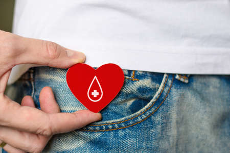 The man calls for blood donation. Red heart with a drop of blood in his hand. Blood donation concept for sick people.の写真素材