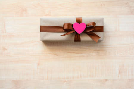 Gift and pink heart on a wooden table. Top view, selective focus on the heart.の写真素材