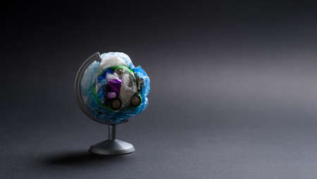 Globe made of garbage on a dark background. The concept of pollution of the planet with garbage. Copy space, selective focus on trash.の写真素材
