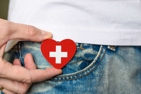 Patriot of the Switzerland! Wooden badge with Switzerland flag in the shape of a heart in a man's hand.の写真素材