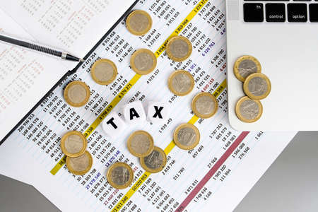 The inscription tax on white cubes and euro coins on the financial table. view from above. The concept of paying taxes in European countries.の写真素材