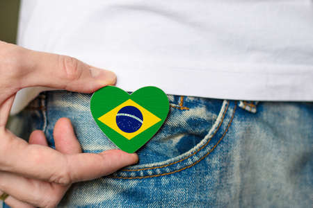 Brazilian resident. Wooden badge with Brazil flag in the shape of a heart in a man's hand.の写真素材