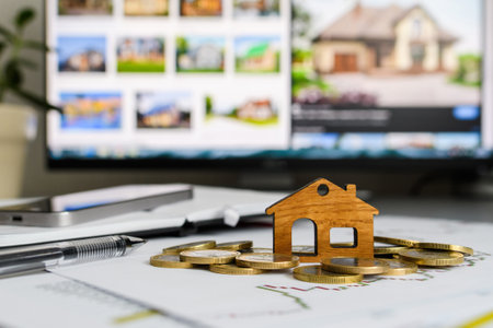 A small wooden house with coins on a computer background with a picture of a house. The concept of...