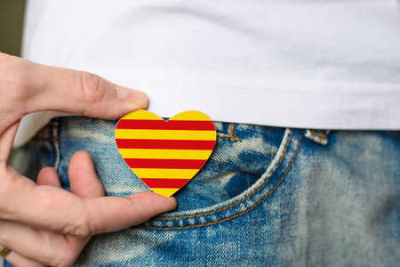 Wooden badge with Catalonia flag in the shape of a heart in a man's hand.の写真素材