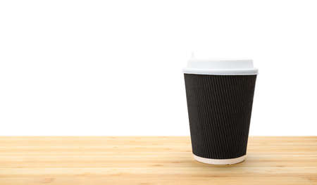One dark large cardboard brown coffee cup stands on a blackboard on a white background. Isolated object, copy space.の写真素材