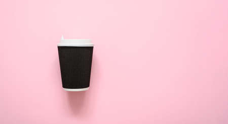 Paper corrugated dark brown cup for coffee on a pink background. copyspace.の写真素材