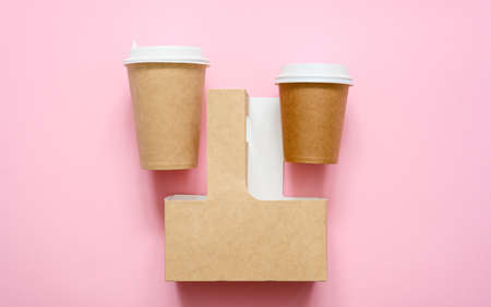 Disposable paper cups and container for carrying cups on a pink background. view from above. Advertisement for food and drink delivery.の写真素材