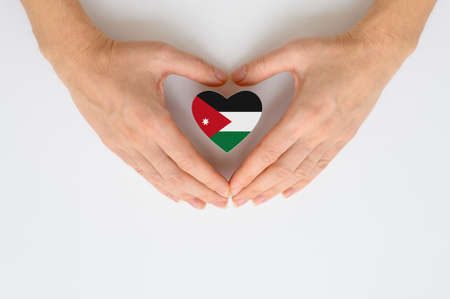 The national flag of Jordan in female hands. The concept of patriotism, respect and solidarity with the citizens of Jordan.の写真素材