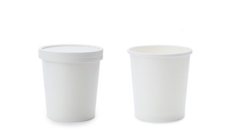 Two white glasses made of paper on a white background. Glass for food or drinks with a lid and without a lid. isolated object. Template for advertising.の写真素材