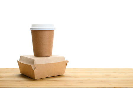 A paper cup for coffee and a container with a hamburger on a wooden table on a white isolated background. copyspace.の写真素材