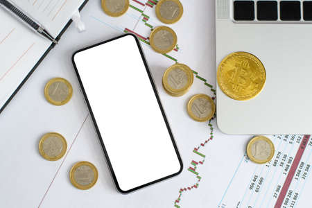 Smartphone with white isolated display next to euro coins and bitcoin coin. Flat lay, mock up.の写真素材