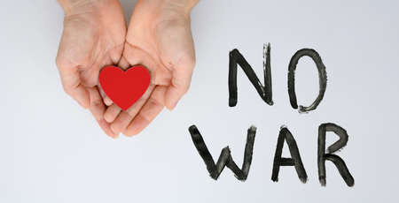 A call for peace and an end to the war. Red heart in female hands next to the black inscription No war.の写真素材