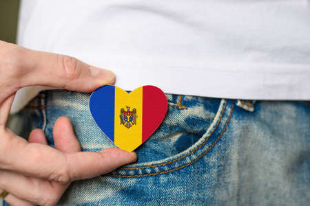 Patriot of the Moldova! Wooden badge with Moldovan flag in the shape of a heart in a man's hand.の写真素材