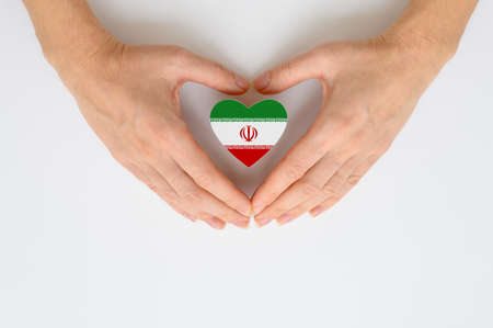 The national flag of Iran in female hands. The concept of patriotism, respect and solidarity with the citizens of Iran.の写真素材