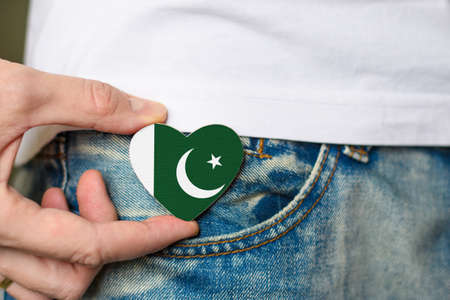 Resident of Pakistan. Wooden badge with Pakistani flag in the shape of a heart in a man's hand.の写真素材