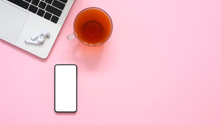 Smartphone, cup of tea and laptop on a pink background. copyspace. Workplace in the office.の写真素材