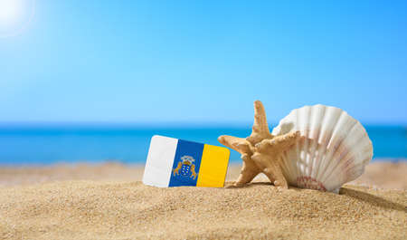 Tropical beach with seashells and Canaries flag. The concept of a paradise vacation on the beaches of the Canaries.の写真素材