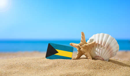 Tropical beach with seashells and Bahamas flag. The concept of a paradise vacation on the beaches of Bahamas.の写真素材