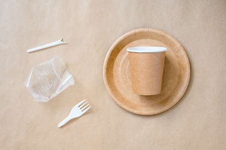 A set of paper eco-friendly tableware next to plastic trash. The concept of protecting the...