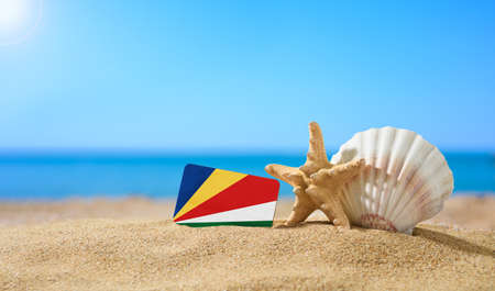Tropical beach with seashells and Seychelles flag. The concept of a paradise vacation on the beaches of Seychelles.の写真素材