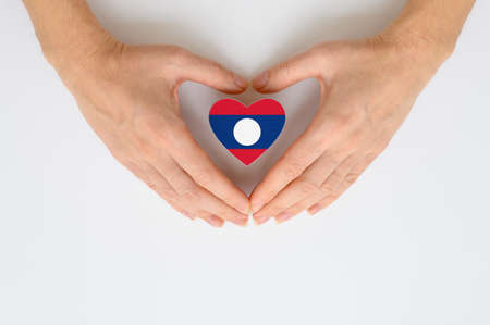 The national flag of Laos in female hands. The concept of patriotism, respect and solidarity with the citizens of Laos.の写真素材