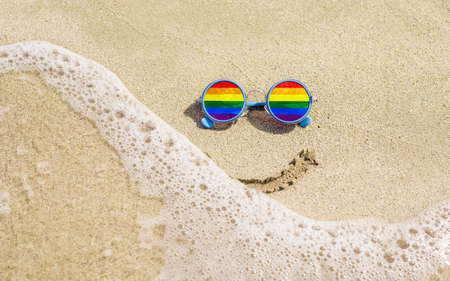 Sunglasses with LGBT flag on a sandy beach. summer travel conceptの写真素材