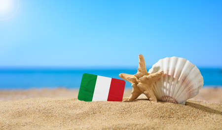 Tropical beach with seashells and Italy flag. The concept of a paradise vacation on the beaches of Italy and Sardinia.の写真素材