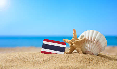 Tropical beach with seashells and Thailand flag. The concept of a paradise vacation on the beaches of Thailand.の写真素材