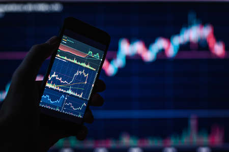 background on a financial theme. Trader charts on smartphone. selective narrow focus.の写真素材