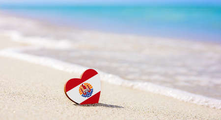 Flag of French Polynesia in the shape of a heart on a sandy beach. The concept of a great holiday on the islands of French Polynesiaの写真素材